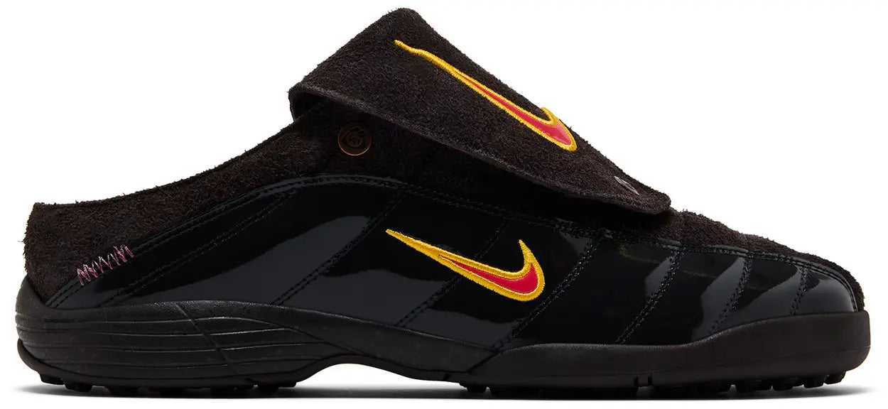 The Kids of Immigrants x Nike T-90 Mule 'Velvet Brown' by Machina Wearable Technology is a black slip-on shoe with a suede upper, shiny lower panels, a fold-over tongue, and a yellow-and-red Nike swoosh on the side.
