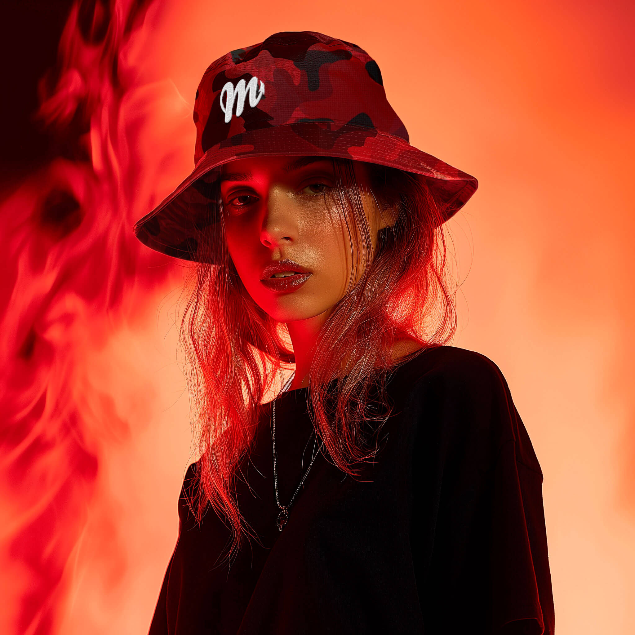 A person wearing a Diablo Bucket Hat by Machina - Wearable Technology and a black shirt stands against a fiery red-orange background. The hat sports a white letter M, perfectly complementing the scorching heat that creates a dramatic and intense atmosphere.