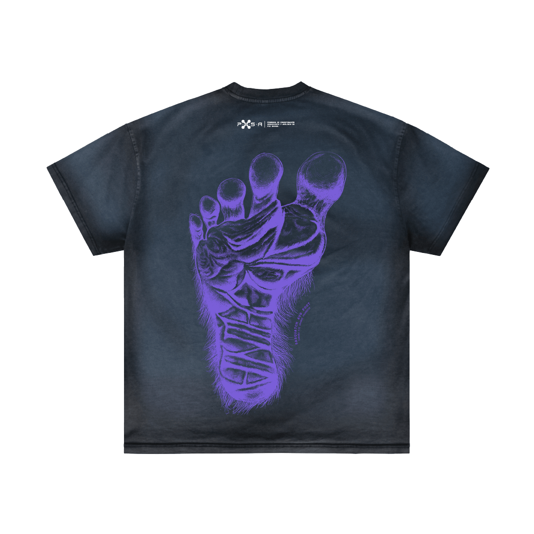 The "Footprint" T-shirt by Machina - Wearable Technology is a black tee that features a large, purple foot adorned with intricate patterns, highlighting Bigfoot's distinctive anatomy on the back. It boasts a subtle tie-dye effect, and there is a small white logo printed near the neckline.
