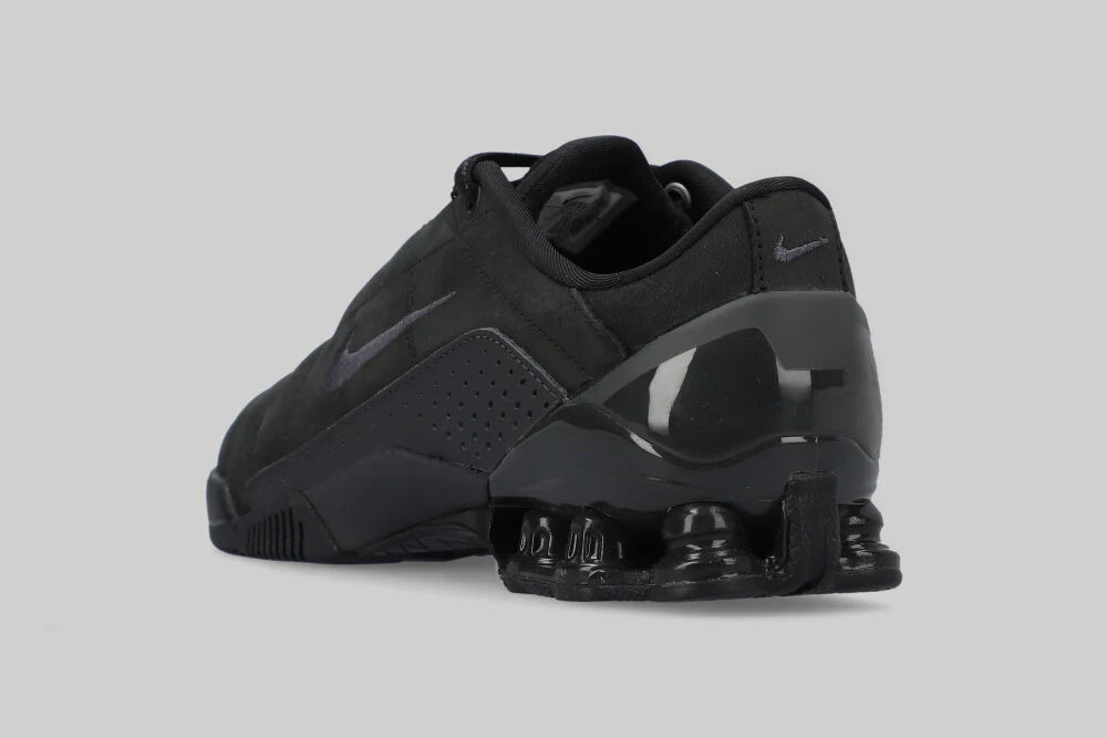 The Machina - Wearable Technology NIKE TOTAL 90 SHOX MAGIA ‘BLACK’ is a black sneaker shown from the back and side, with a dark air-cushioned sole, subtle swoosh logos on heel and side, and durable genuine leather construction.
