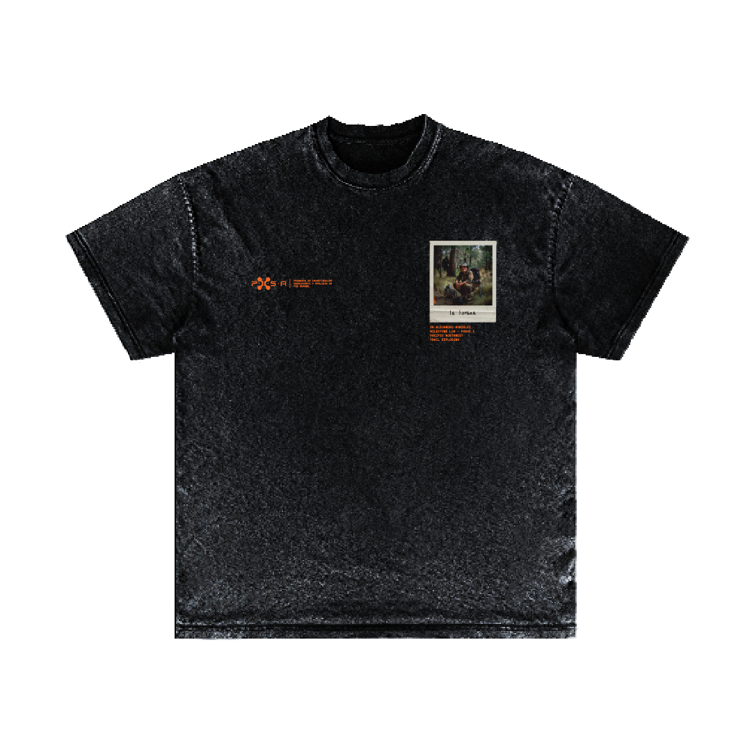 Introducing the La Sombra T-shirt by Machina - Wearable Technology: a black tee featuring a graphic and text design on the front. The left side showcases small orange lettering, while the right side displays a square image of Bigfoot with additional text beneath it. This shirt's fabric boasts a slightly textured appearance, capturing the essence of rugged wilderness adventure.