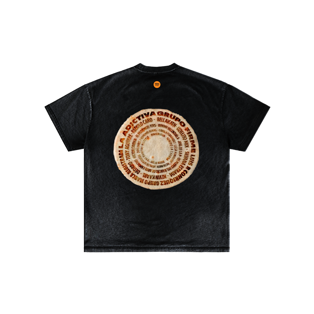 The Tortilla Milagro T-shirt from Machina - Wearable Technology is made from soft Mexican cotton and showcases a black base with a large circular design on the back featuring vibrant shades of orange and brown, reminiscent of the lively patterns found at the Mexcla festival.