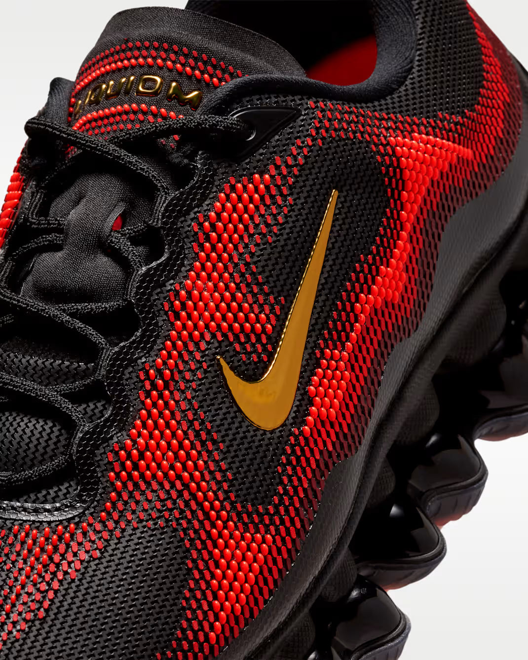Close-up of the Machina Wearable Technology Air Liquid Max 'Bright Crimson Fire Red' shoe featuring a black and crimson colorway, gold accent, textured upper, black laces, and a unique wavy sole design.