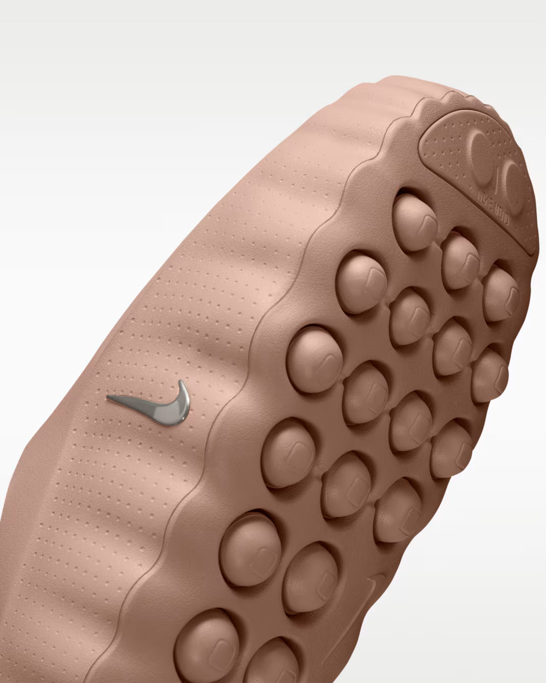 Close-up of a dusty rose Mind 001 comfort footwear sole by Machina Wearable Technology, featuring a large, rounded tread pattern and a metallic silver swoosh logo on the side.