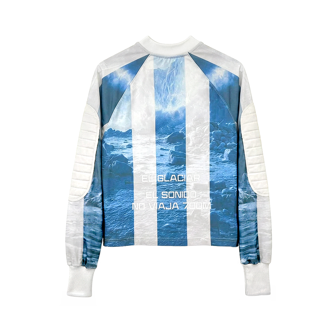 The Machina - Wearable Technology GLACIAR 700M is a long-sleeve jacket with white and light blue stripes, inspired by Argentina’s World Cup goalie jersey, featuring glacier and waterfall imagery with "El Glaciar," "El Sonido," and "No Viaja Today" on the back.