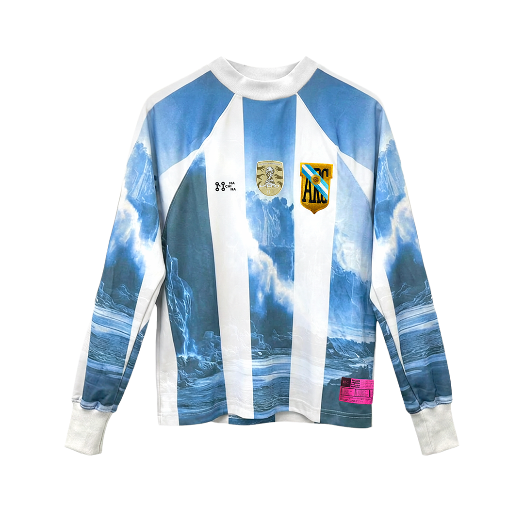 The GLACIAR 700M by Machina - Wearable Technology is a long-sleeve goalkeeper jersey with sky-blue and white vertical stripes, ocean wave graphics, three embroidered chest patches, and a small pink tag near the bottom right hem.