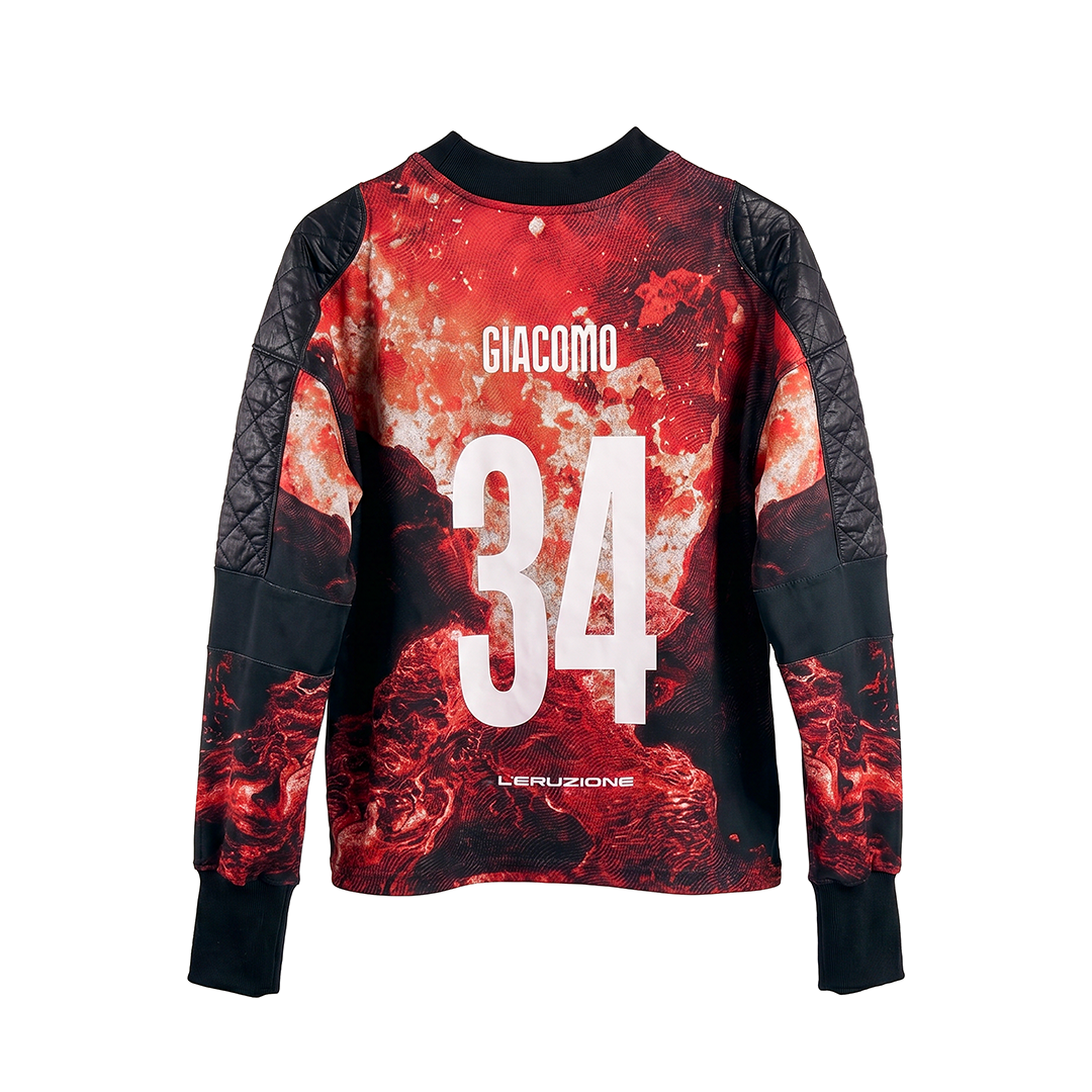 The L'ERUZIONE by Machina - Wearable Technology is a long-sleeve Italian football shirt with red and black fiery patterns, black quilted sleeves, GIACOMO and 34 in bold white print, and L'ERUZIONE at the bottom—echoing the 1934 World Cup era.