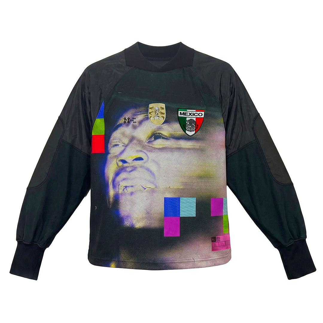 The CAMARENA 40235 by Machina - Wearable Technology is a long-sleeve black goalkeeper jersey with colorful pixelated blocks, a large faded face on the front, and two badges: one gold emblem and one with "Mexico 70" and a shield.