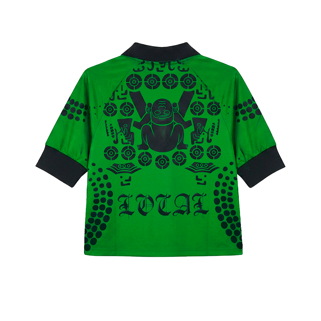 The "MEXICANOS AL GRITO DE GUERRA" shirt by Machina - Wearable Technology is a green short-sleeve top with black collar and cuffs, featuring a bold lucky cat graphic and circular motifs, plus LOLA text on the back for Huastec warrior style.