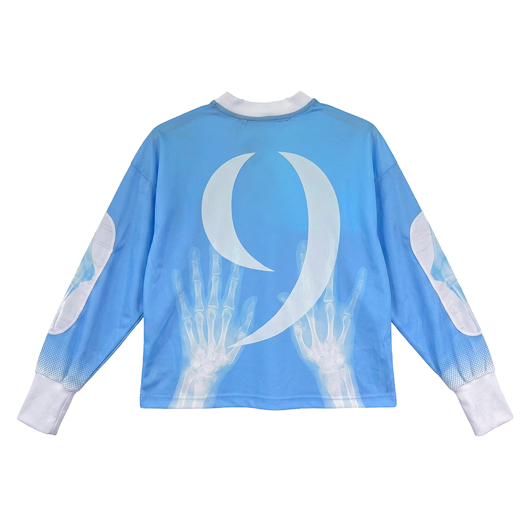 The LA GARRA by Machina - Wearable Technology is a blue long-sleeve goalkeeper jersey with a bold white semicolon, hand X-rays on the back, white cuffs, and oval patches—an eye-catching tribute to World Cup history.