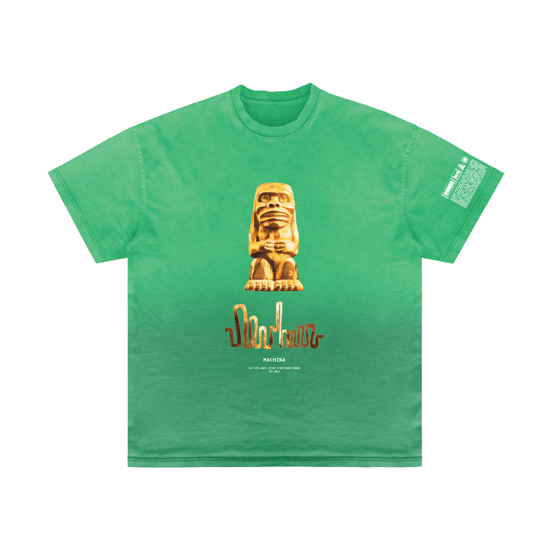 A green Quimbaya T-shirt by Machina - Wearable Technology showcases a central print of a stylized, textured statue inspired by the Quimbaya people, accompanied by text below it. Additional text adorns one sleeve. The T-shirt blends cultural motifs with modern typography, infusing Colombian vibes throughout the piece.