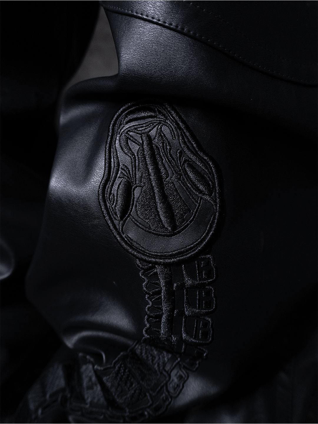 Close-up of the Machina All-Black Eco Leather Osseous Full Zipper Set: embossed abstract design and BBB-stitched details evoke ceremonial armor, enhanced by dramatic lighting.