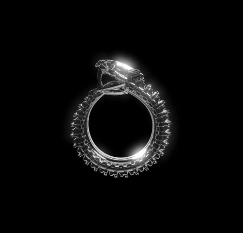 The Ouroboros Chunky Ring by Machina - Wearable Technology features a large central gemstone and a uniquely textured band with tire-like grooves, reflecting biomechanical jewelry design. Shown in profile against a black background.