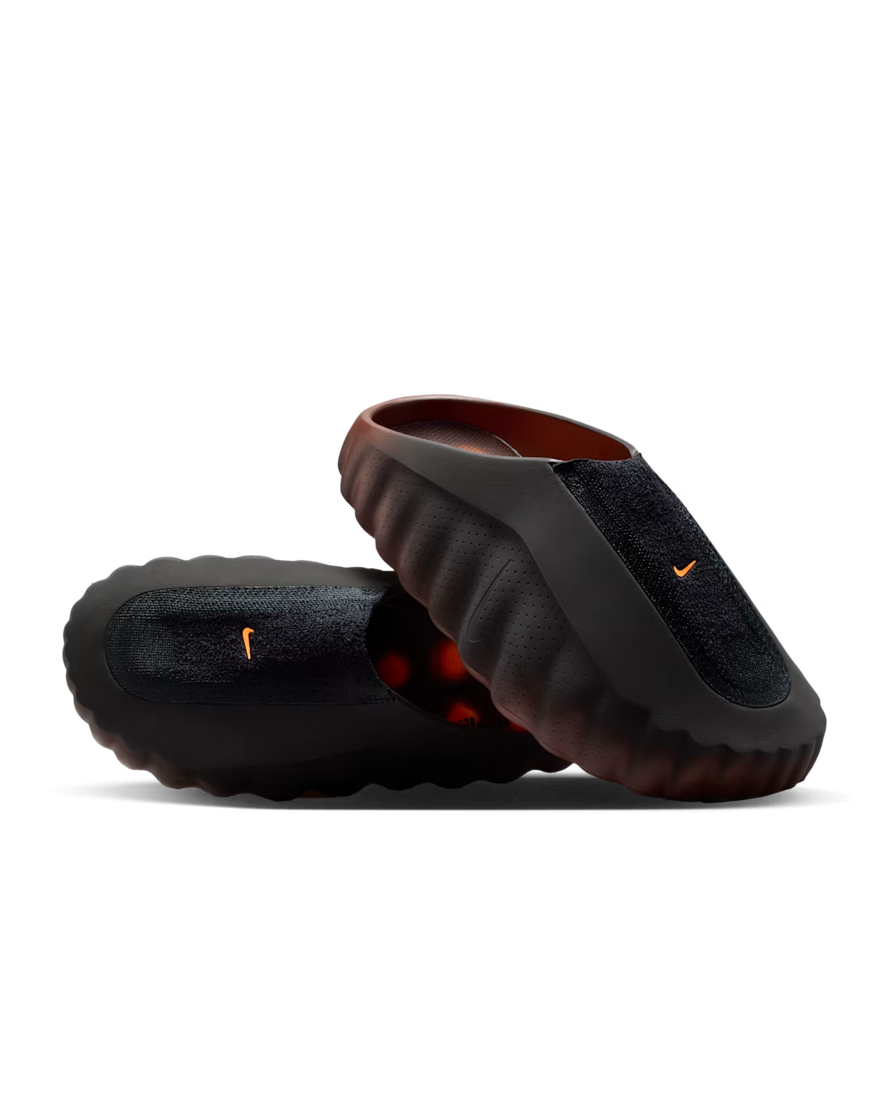 Two black slip-on Machina Wearable Technology Mind 001 Flyknit Bronze Eclipse clogs with wavy, textured soles. One stands upright and the other lies on its side, displaying both the top and sole.