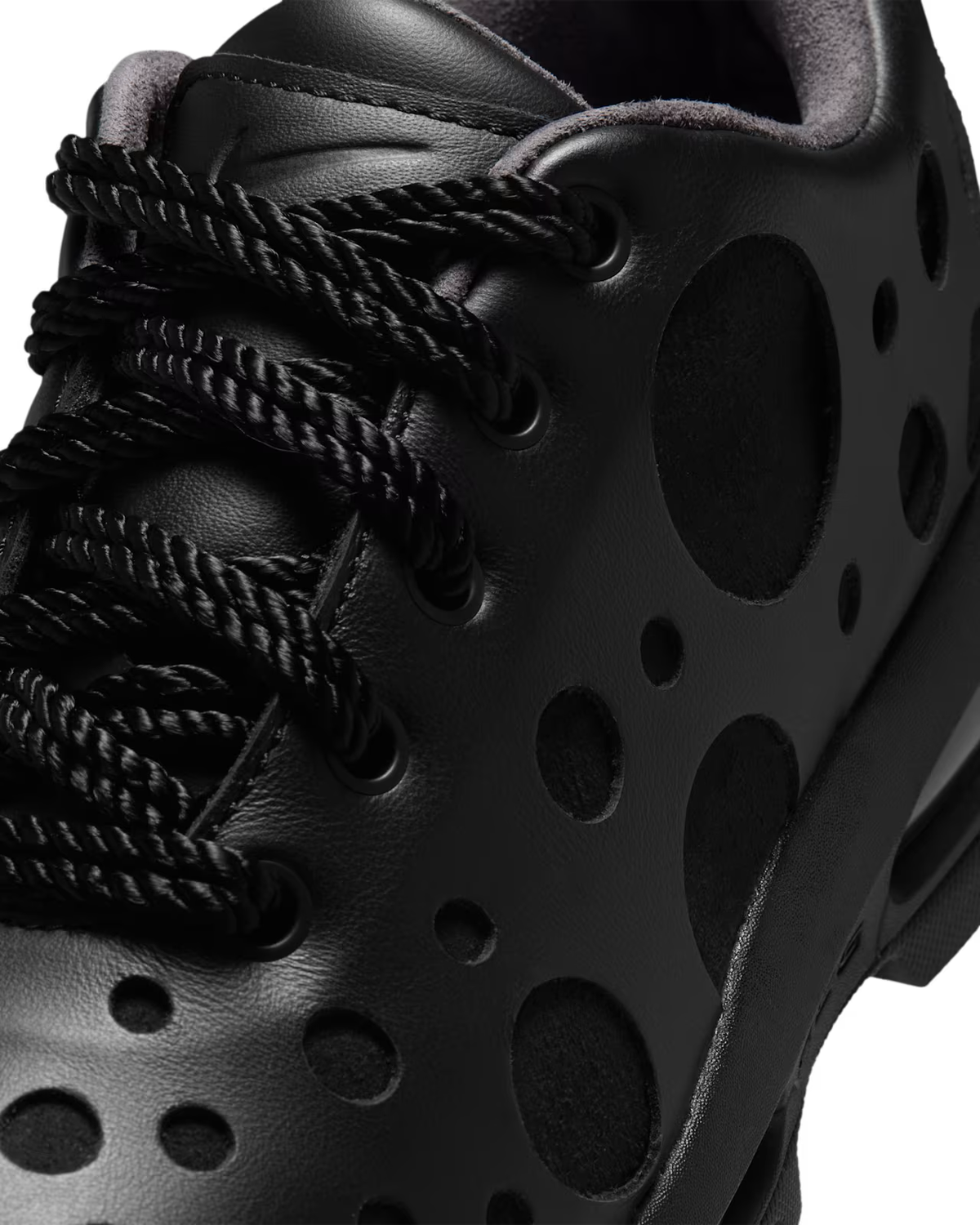 Close-up of the Air Max Goadome Low [ Black ] by Machina Wearable Technology, featuring distinctive round cut-out patterns on the side, black laces, and a sleek matte leather finish. Inspired by the rugged style of the iconic Nike Air Max Goadome, these black sneakers offer subtle Air cushioning for enhanced comfort—delivering both functionality and refined style.