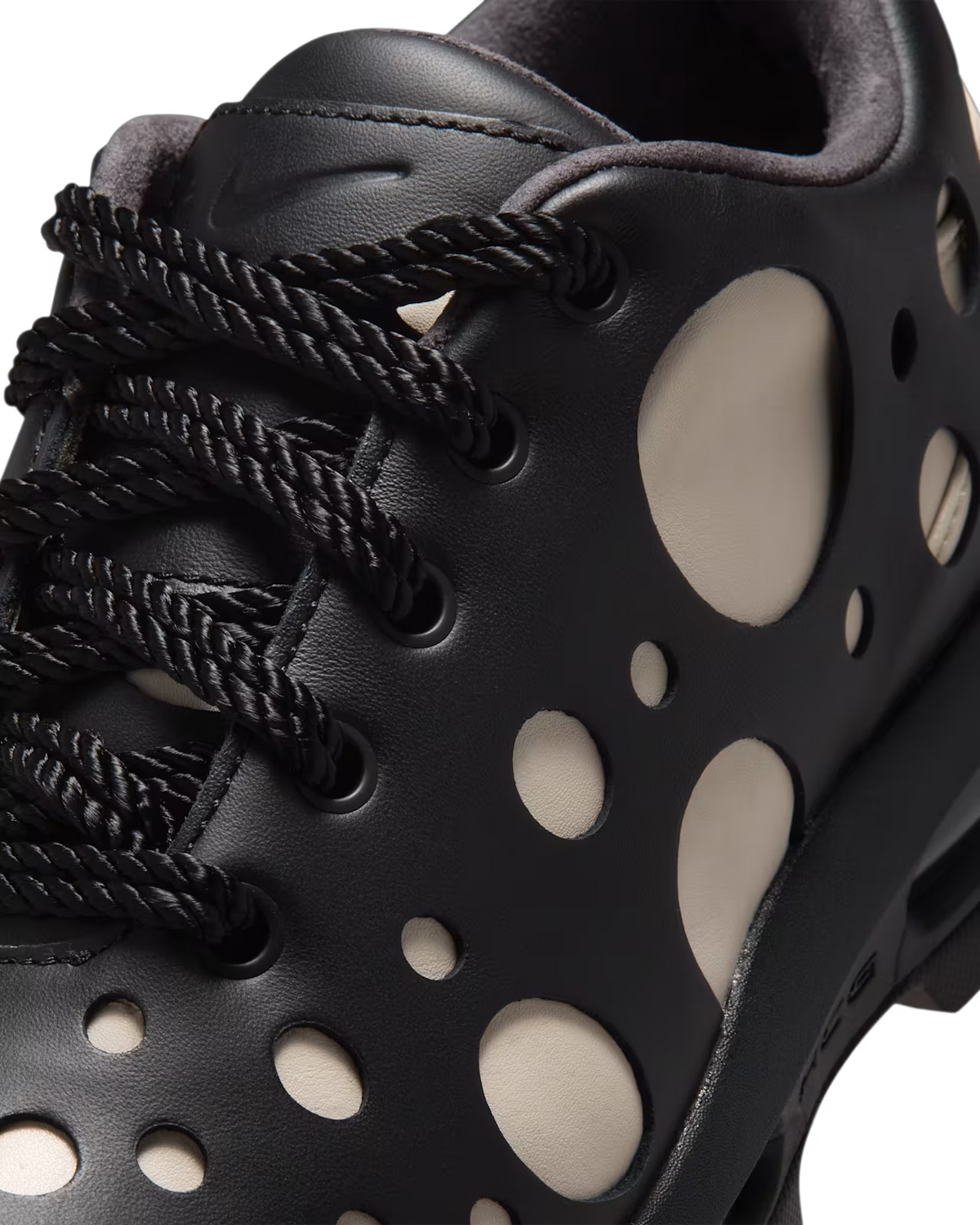 Close-up of the Machina Wearable Technology Air Max Goadome Low sneaker in Light Orewood Brown and Black, featuring large circular cutouts that reveal a lighter layer beneath, neutral color accents, black rope laces, and visible Machina branding on the tongue.