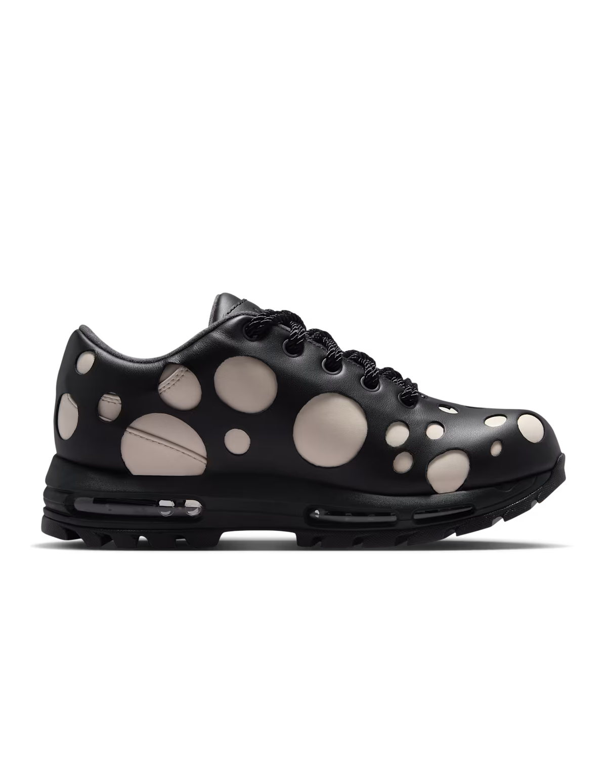A sneaker from Machina Wearable Technology, the Air Max Goadome Low in Light Orewood Brown and Black, showcases an upper with large and small beige circular spots, a chunky black sole with visible air cushioning, and a stylish mix of neutral tones.
