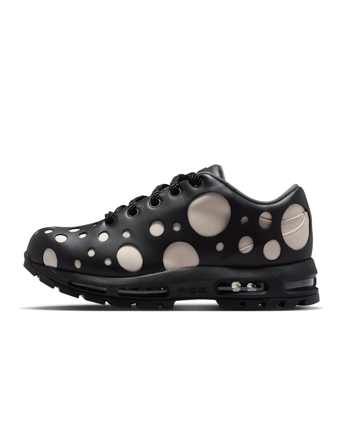 Introducing the Air Max Goadome Low by Machina Wearable Technology in Light Orewood Brown and Black—a sneaker inspired by classic outdoor boots. This design features black uppers accented with beige circular cutouts of varying sizes, revealing the contrasting inner material beneath. Complete with black laces and a visible air cushion embedded in the heel, it expertly blends neutral tones for a sleek, rugged look.