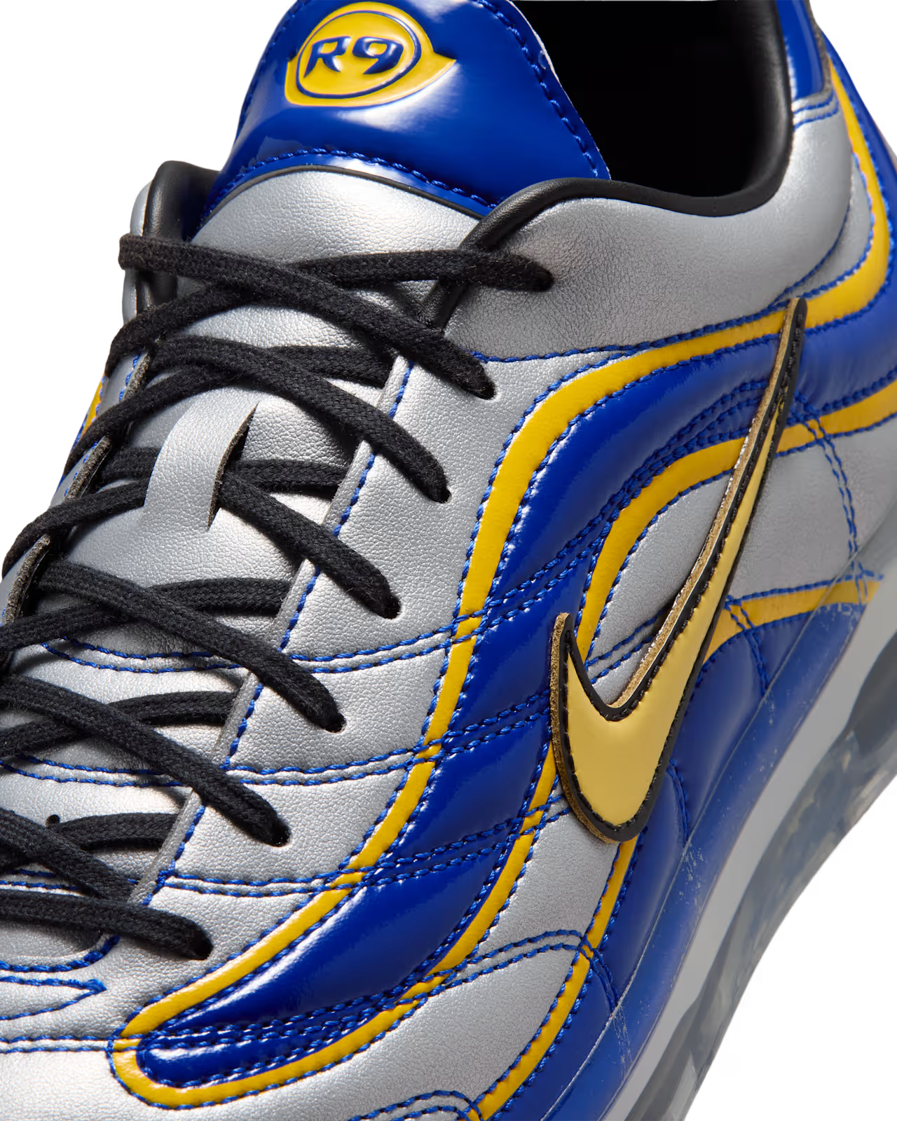 Close-up of a silver, blue, and yellow Machina Wearable Technology Cryoshot Mercurial Vapor R9 OG / PACOTE sneaker with black laces and a bold yellow swoosh. The tongue features a CRYOSHOT R9 logo at the top, making this online exclusive design a standout addition to any collection.