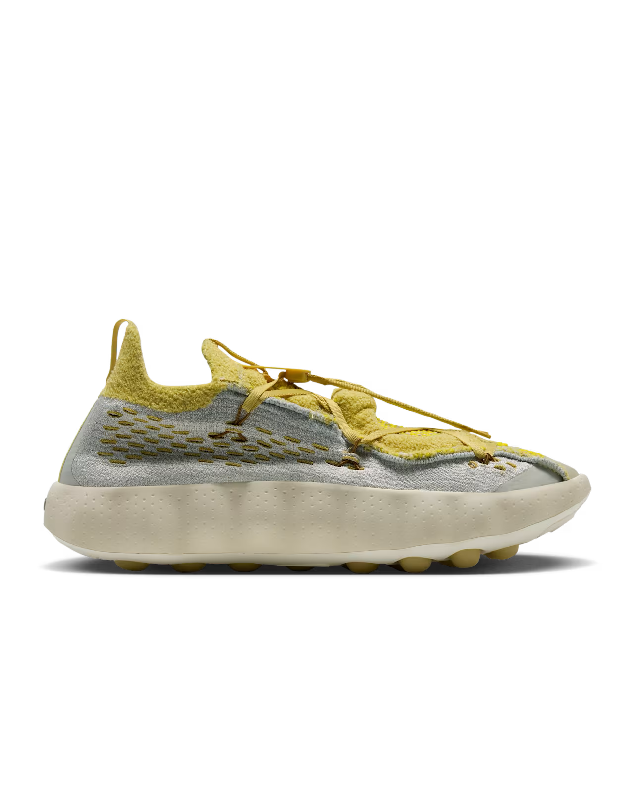 A side view of the Machina Wearable Technology Mind 002 Light Bone and Saturn Gold sneaker, featuring a textured sole, a distinctive knit upper, and an unconventional lacing system.