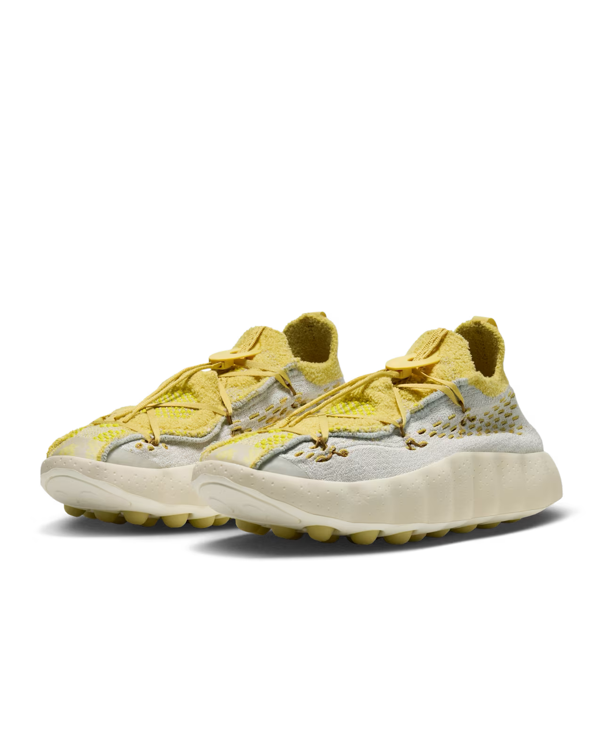 A pair of Machina Wearable Technology Mind 002 sneakers in Light Bone and Saturn Gold, featuring a knit texture, chunky sole, and unique lace design, displayed on a white background.