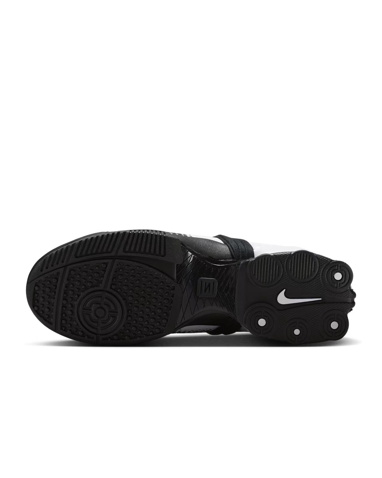 The image shows the black sole of a Machina Wearable Technology Total 90 Shox Magia White and Black football shoe, featuring circular traction patterns, the brand's logo, and three rounded protrusions near the heel. The colorway combines classic white and black details for a bold look.