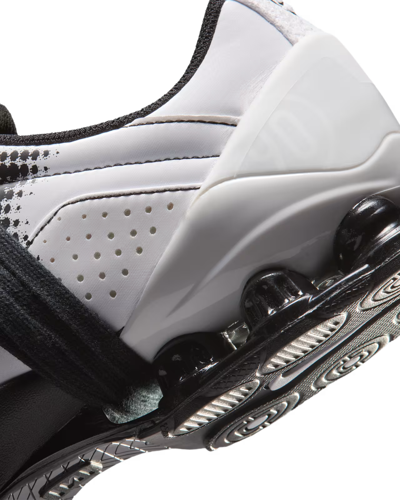 Close-up of a Machina Wearable Technology Total 90 Shox Magia White and Black football shoe, featuring perforated detailing, a black strap, and a clear, cushioned sole with circular patterns on the bottom.