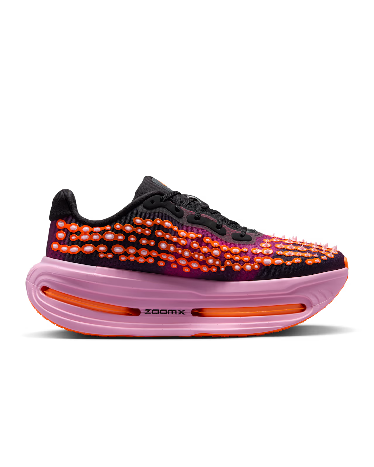 Introducing the Nike Vomero Premium “Otaku Approved” by Machina Wearable Technology: This striking black sneaker features bright orange and red textured spots on its upper, complemented by bold orange accents and a thick pink midsole. Designed as one of Nike Vomero Premium’s top-tier maximum-cushion running shoes, it boasts a ZoomX platform with visible air units labeled “ZoomX” for exceptional comfort and responsiveness.