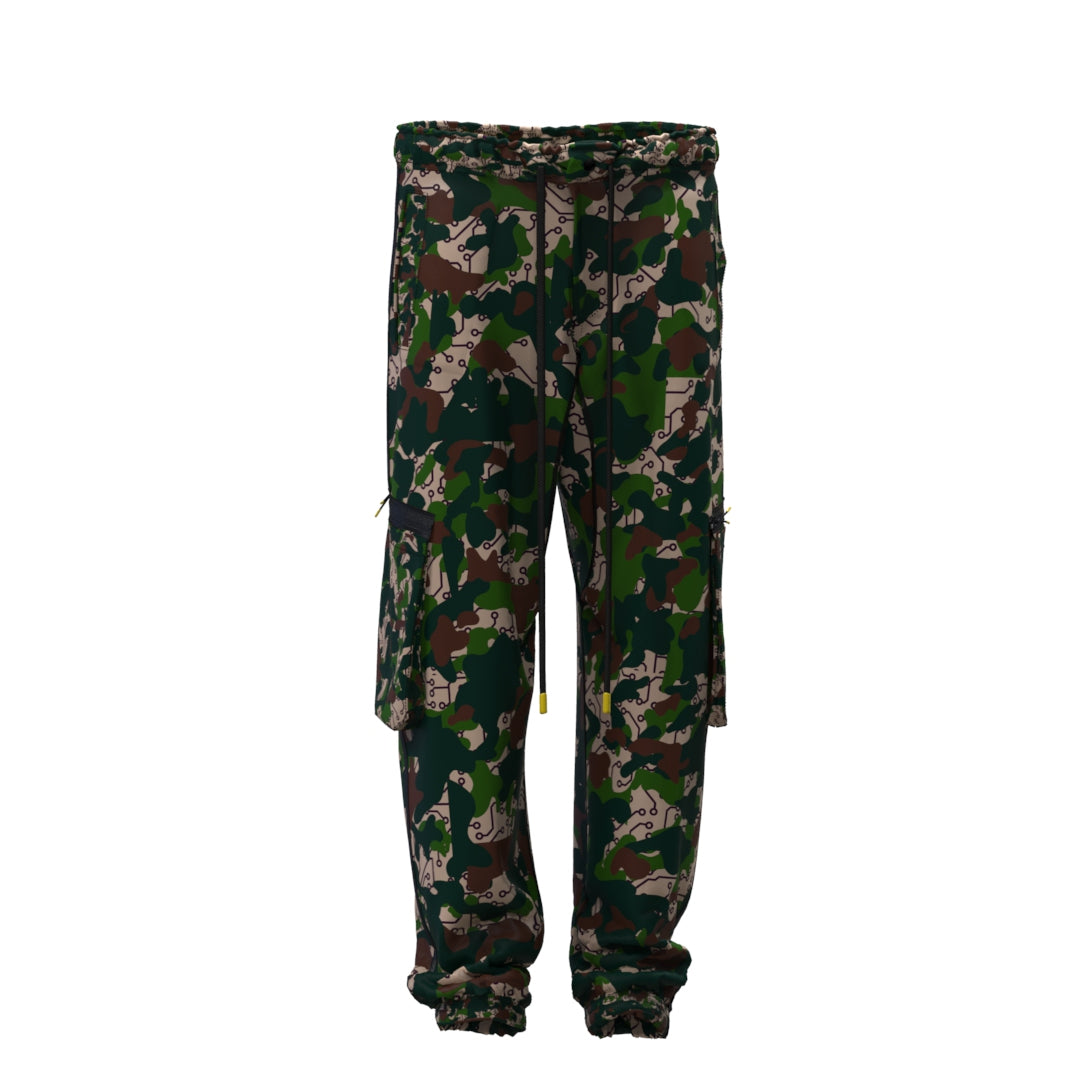 Desierto Technical Pants by Machina - Wearable Technology are crafted from recycled fabric and showcase a camouflage desierto pattern in green, brown, and beige. These pants come with elastic cuffs, adjustable waist drawstrings, and multiple side pockets, set against a plain white background.