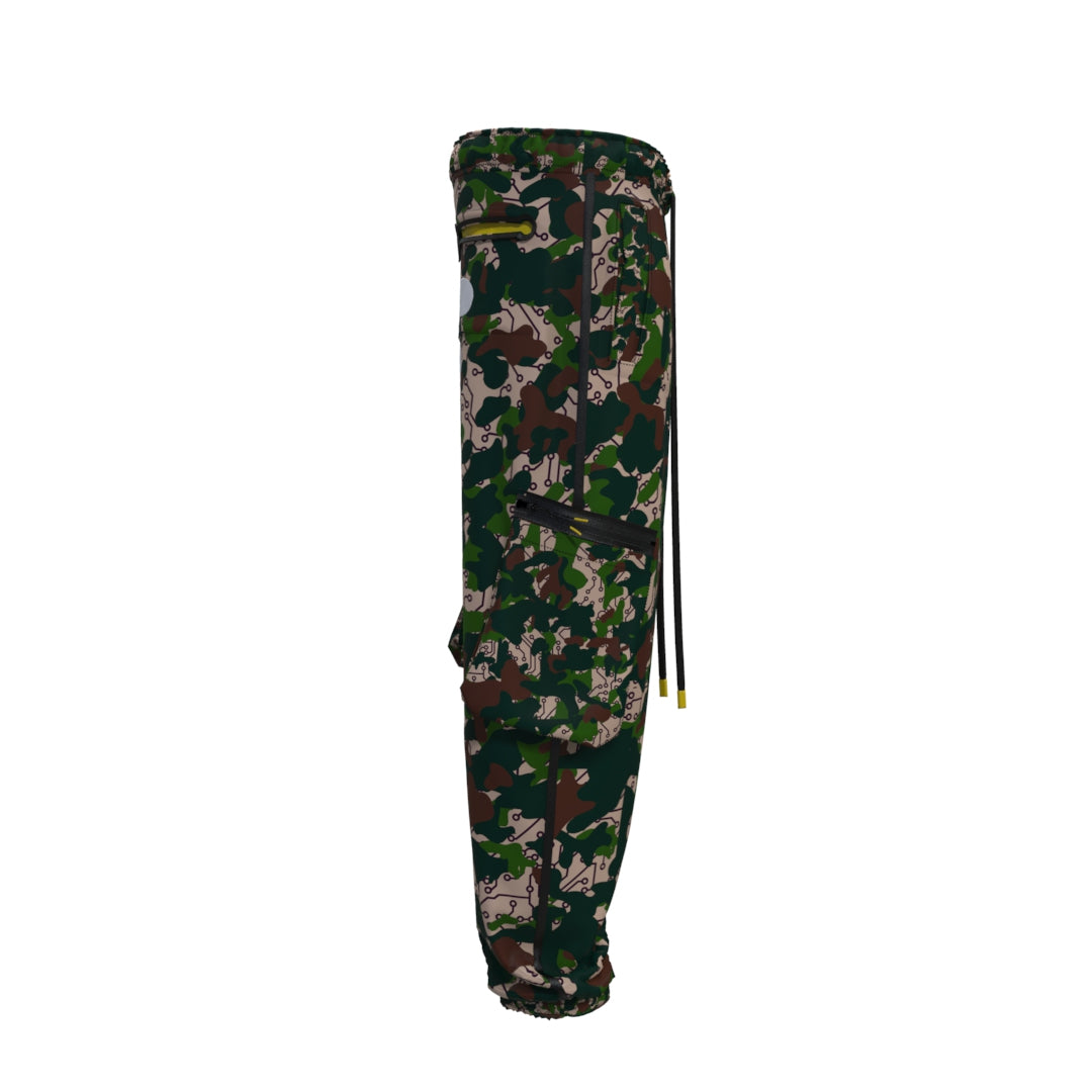 Side view of Desierto Technical Pants in a green, brown, and black camouflage pattern by Machina - Wearable Technology. Made from recycled fabric, these technical cargo pants include multiple pockets and an elastic waistband with drawstrings. The lightweight material makes them perfect for outdoor adventures.