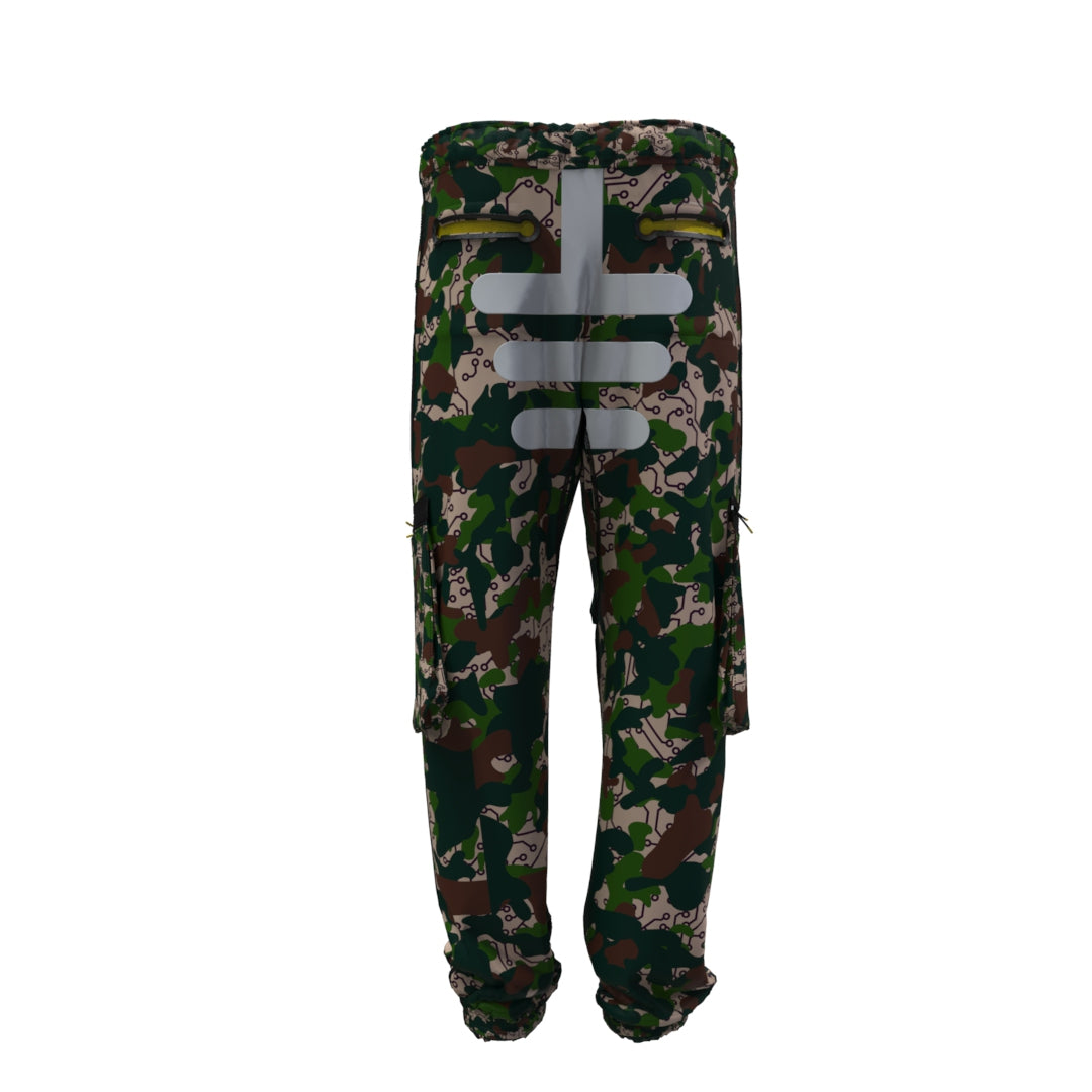 Desierto Technical Pants by Machina - Wearable Technology are crafted from recycled fabric and feature abstract patterns with reflective grey stripes on the back. The desierto camouflage design incorporates dark green, brown, and tan colors, offering adjustable leg openings and multiple pockets.