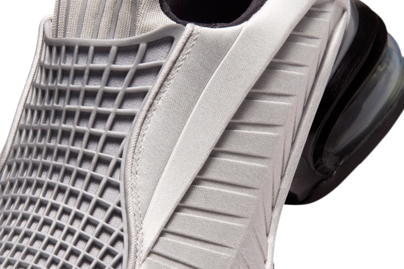 Close-up of a modern lifestyle sneaker, specifically the Machina Wearable Technology Nike Air Max Dolce “Metallic Silver,” featuring a unique textured grid and ribbed pattern on the upper, shown in metallic silver and black colors.