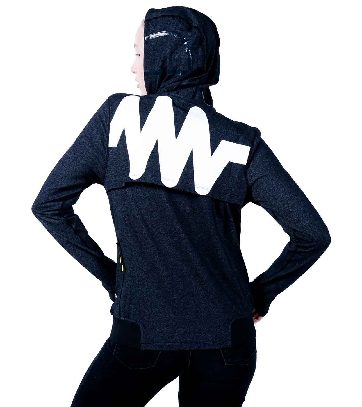 A person stands confidently with hands on hips, wearing the MACHINA HOODIE by Machina - Wearable Technology. This sleek, dark hoodie features a hood and a bold white zigzag design on the back, epitomizing fashion tech against a plain white background.