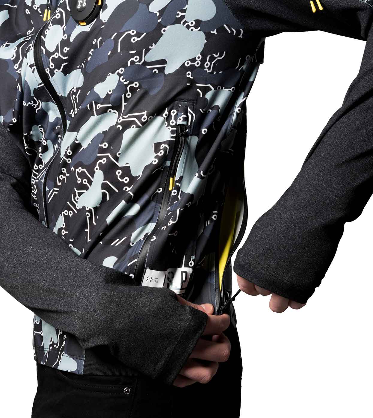 A person wearing the Machina - Wearable Technology BLACK-CAMO BOMBER JACKET with long sleeves is adjusting a zipper. The jacket showcases a mix of abstract designs and circuit-like patterns in shades of blue, green, and black, with the image highlighting the side profile.
