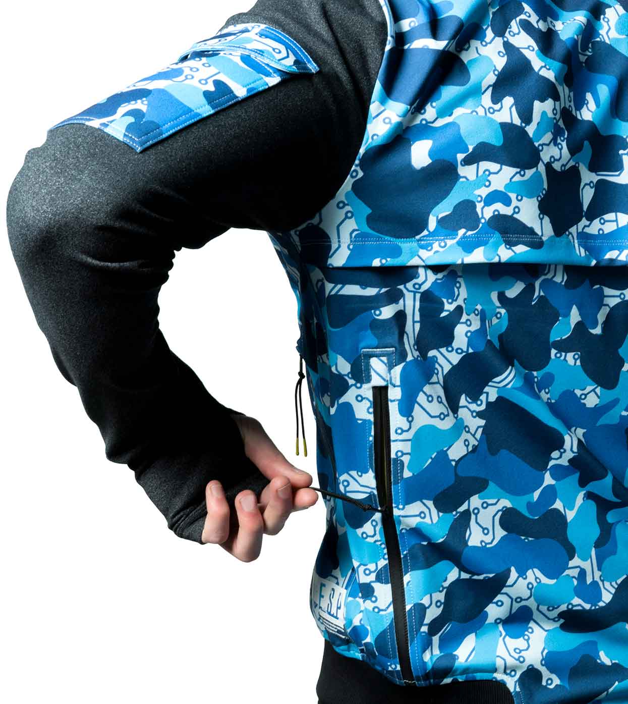 A person clad in the BLUE-CAMO BOMBER JACKET by Machina - Wearable Technology adjusts the zipper on a back pocket. This jacket, crafted from sustainable fabrics, showcases long black sleeves and a patch on the upper arm with its distinctive blue and white camouflage pattern.
