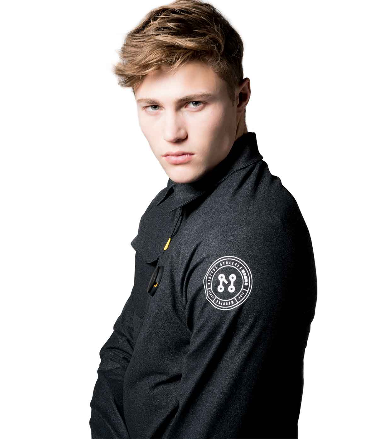 A person with short hair models the BLACK CASUAL JACKET by Machina - Wearable Technology, noted for its distinctive sleeve emblem, against a white backdrop.