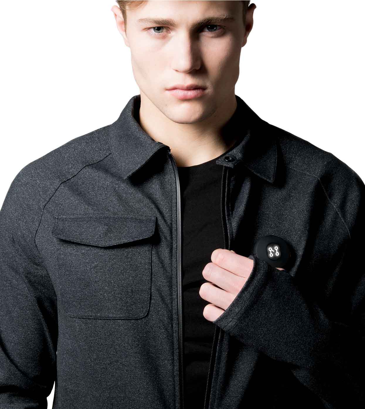 A person wearing a black casual jacket from Machina - Wearable Technology has the zipper slightly open, revealing their stylish appearance. The jacket is designed with a high collar and made from sustainable fabrics, featuring a chest pocket. Underneath, they wear a black shirt against a plain white background.