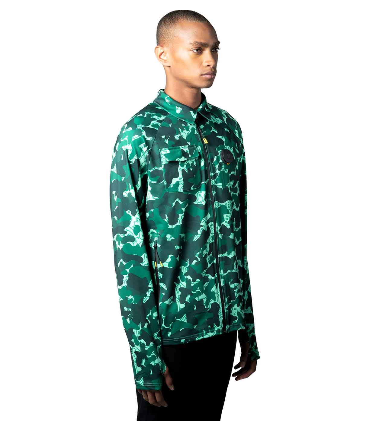 A person wearing the Machina - Wearable Technology AQUA-CAMO CASUAL JACKET stands against a white background. This smart casual jacket showcases a blend of lighter and darker green camo shades with button details on the long sleeves. The person is facing forward with a neutral expression.