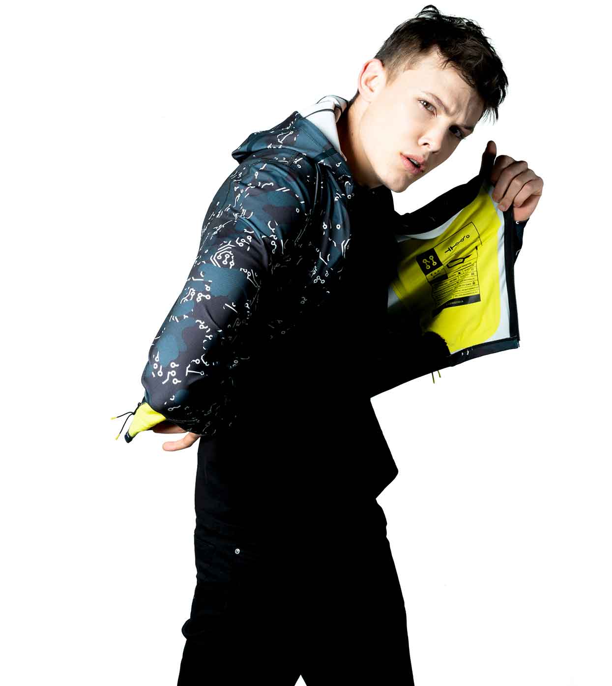 A person stands with a quizzical expression, wearing the ELECTRIC WHITE HOODIE by Machina - Wearable Technology, showcasing a sophisticated dark pattern. The hoodie is partly open to reveal its striking bright yellow lining, perfectly blending style and innovation against a crisp white background.