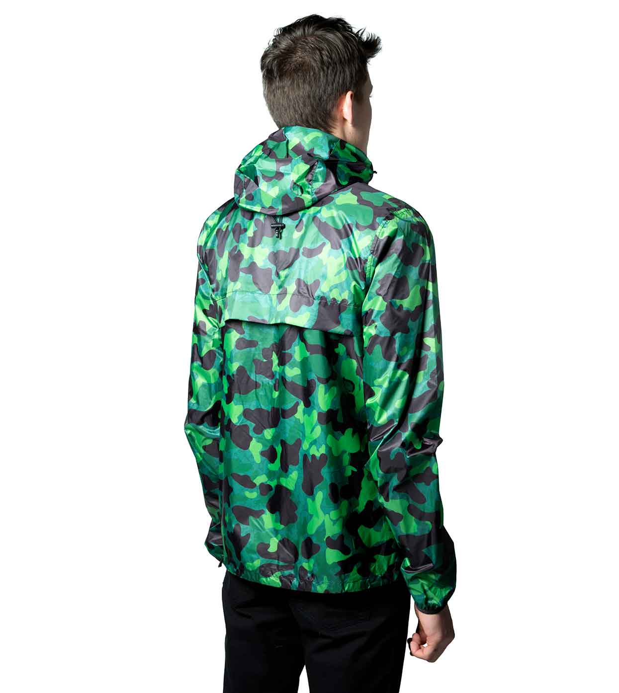 A person clad in the GREEN-CAMO WINDBREAKER from Machina - Wearable Technology stands with their back turned. This ultralight nylon jacket features an assortment of green and black camouflage patterns, while the individual sports short dark hair and pairs the windbreaker with black pants against a white background.