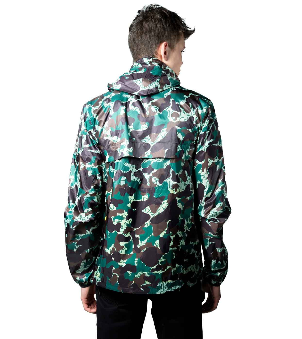 A person dons the JARHEAD CAMO WINDBREAKER by Machina - Wearable Technology, featuring a green and brown camouflage pattern with a hood, standing with their back to the camera. The glossy finish of this smart windbreaker, crafted from ultralight nylon, displays various shades of green and brown against the plain white background.