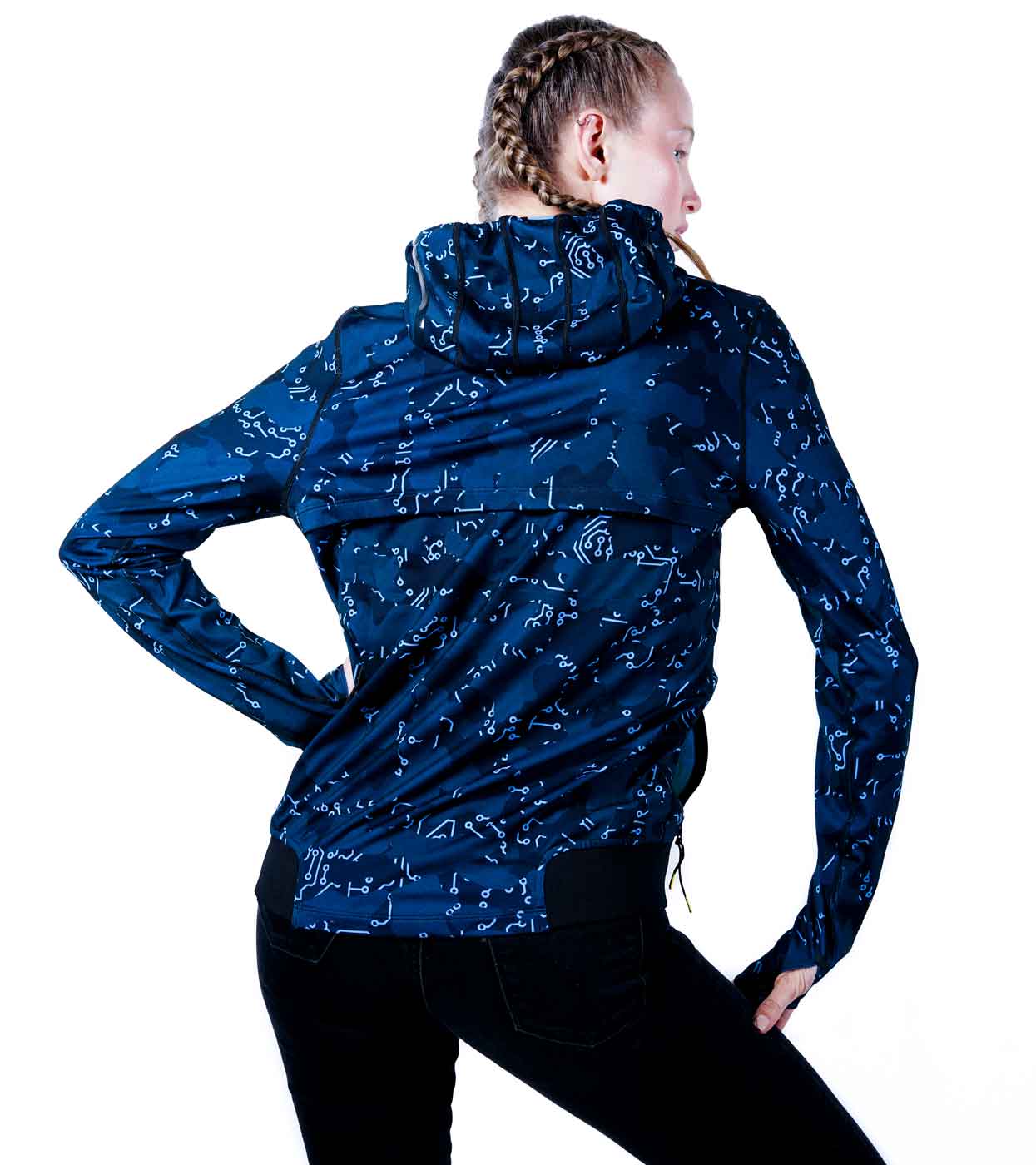 A person with braided hair wears the ELECTRIC BLUE HOODIE from Machina - Wearable Technology, featuring a white abstract pattern on a navy blue background. They stand with their back to the camera, slightly turned to the left. The hoodie comes with an advanced hood design and is paired seamlessly with black pants, capturing the essence of modern fashion tech style.
